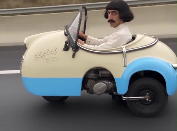 Abu Shalab driving a small cream and blue car, an example of a finished character video